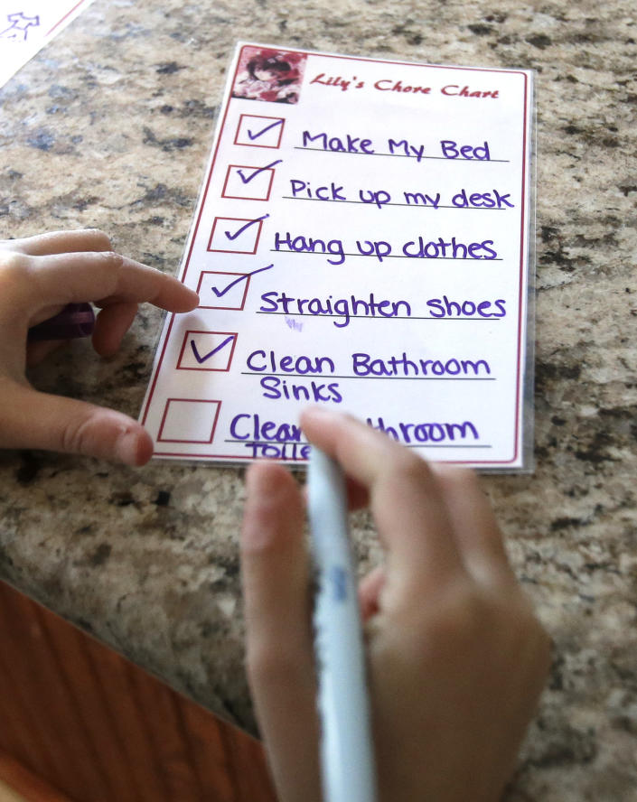 In this Saturday, Feb. 8, 2014 photo, Lily Cherry, 8, checks off her list of household chores at her home in Kingwood, Texas. Lily makes her bed, prepares breakfast for herself and little brother, Aiden, 6, as well as does other household chores. Her mother, Andrea Cherry, has passed on her childhood practice of doing chores to her own children believing it gives them a sense of family responsibility. (AP Photo/Pat Sullivan)