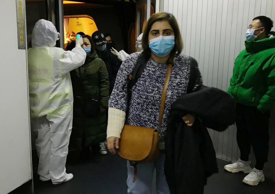 Health Officials in hazmat suits check body temperatures of passengers arriving from the city of Wuhan Wednesday, Jan. 22, 2020, at the airport in Beijing, China. Nearly two decades after the disastrously-handled SARS epidemic, China’s more-open response to a new virus signals its growing confidence and a greater awareness of the pitfalls of censorship, even while the government is as authoritarian as ever. (AP Photo Emily Wang)