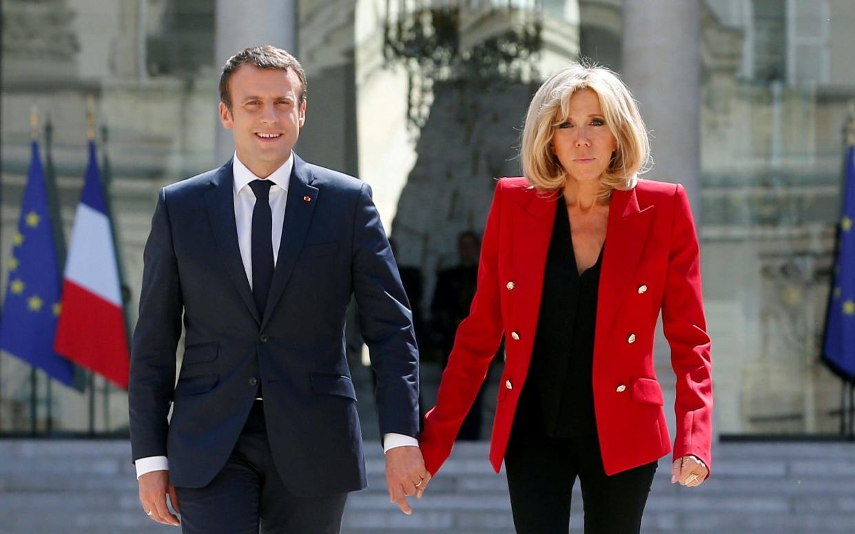 French President Emmanuel Macron and his wife Brigitte Macron walk in the Elysee Palace courtyard  - REUTERS