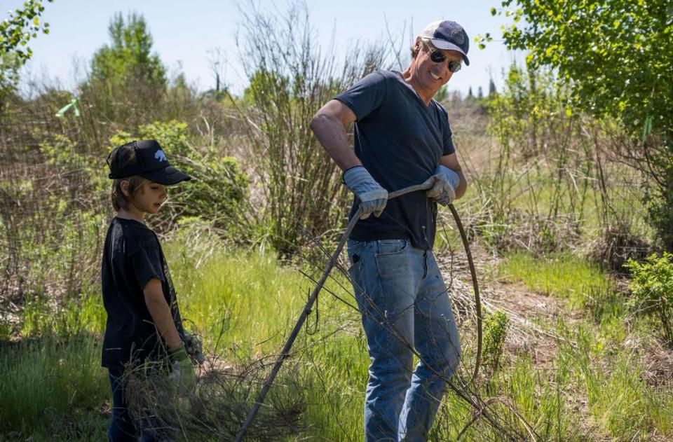 Gov. Gavin Newsom, alongside his son Dutch, pulls on an old irrigation line as part of the cleanup during the Earth Day celebration at Soil Born Farms on Saturday in Rancho Cordova. The event was hosted by First Partner Jennifer Siebel Newsom, in partnership with the California Department of Food and Agriculture and California Volunteers.