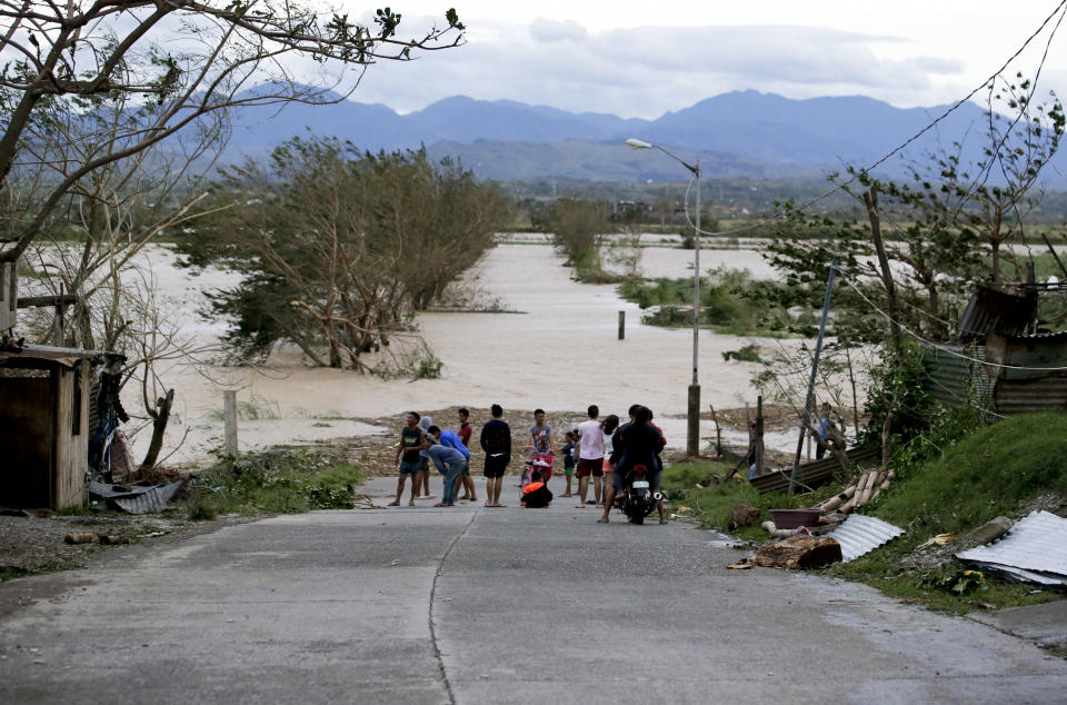 FILE - In this Saturday, Sept. 15, 2018, photo, residents stand by a flooded road following the onslaught of Typhoon Mangkhut in Tuguegarao City in Cagayan province, northeastern Philippines. (AP Photo/Aaron Favila, File)