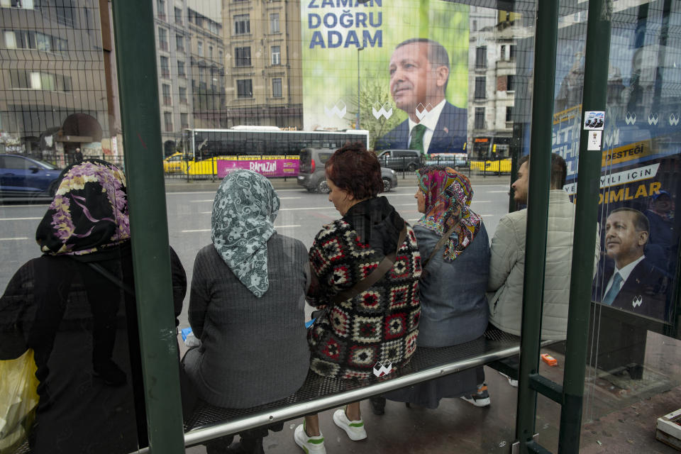Passengers wait at a bus stop next to election campaign billboards of Turkish President and People's Alliance's presidential candidate Recep Tayyip Erdogan is displayed in Istanbul, Turkey, Thursday, May 4, 2023. (AP Photo/Emrah Gurel)