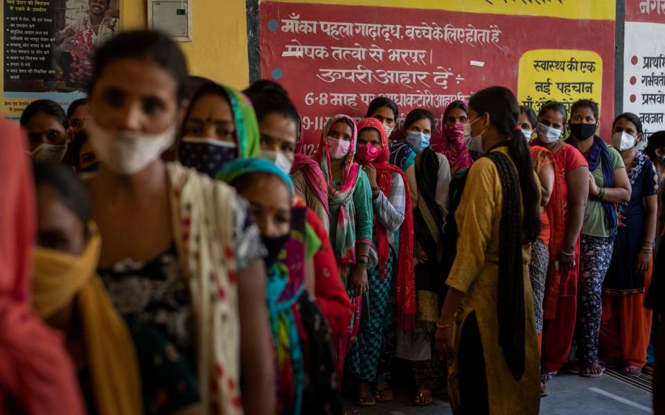 Women wait in line for the arrival of vaccines during a vaccination drive in Noida, a suburb of New Delhi - AP