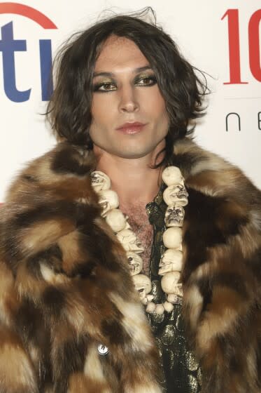 A person with sparkling eye make up and dark hair wearing a fur coat