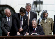 <p>Israeli Foreign Minister Shimon Peres signs the peace accord between Israel and the PLO on Sept.13, 1993 while (L-R) Israeli Prime Minister Yitzhak Rabin, US presidential aide John Podesta, President Bill Clinton and PLO chairman Yasser Arafat look on. (Gary Hershorn/Reuters) </p>