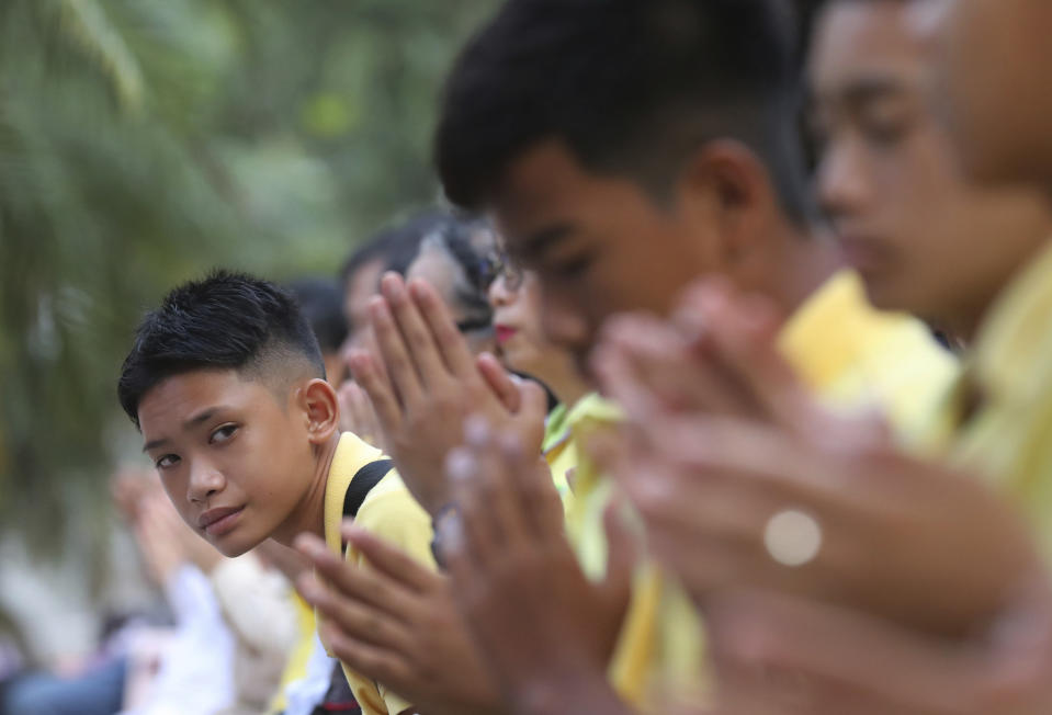 Mongkol Boonpiam, left, a member of the Wild Boars soccer team who were rescued from a flooded cave, watches his teammates during a religious ceremony near the Tham Luang cave in Mae Sai, Chiang Rai province, Thailand Monday, June 24, 2019. The 12 boys and their coach attended a Buddhist merit-making ceremony at the Tham Luang to commemorate the one-year anniversary of their ordeal that saw them trapped in a flooded cave for more than two weeks. (AP Photo/Sakchai Lalit)