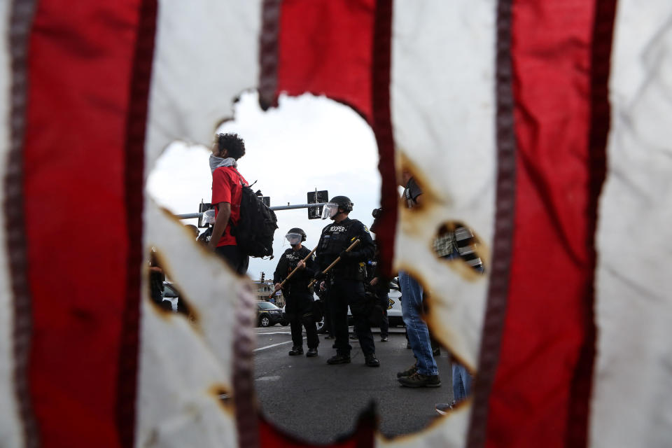 <p>Police in riot gear and a protester stand near a burned U.S. flag after the not guilty verdict in the murder trial of Jason Stockley, a former St. Louis police officer charged with the 2011 shooting of Anthony Lamar Smith, in St. Louis, Mo., Sept. 17, 2017. (Photo: Lawrence Bryant/Reuters) </p>