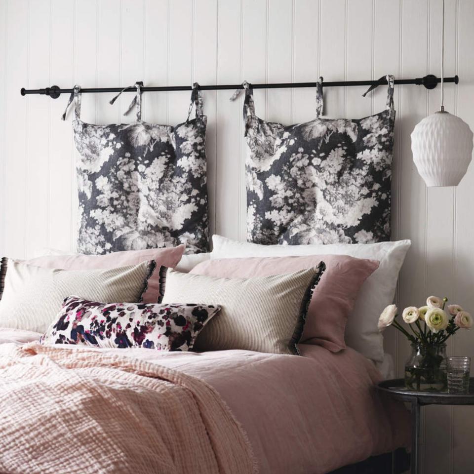 Bed, pink bedding, hanging floral cushion headboard in a small bedroom