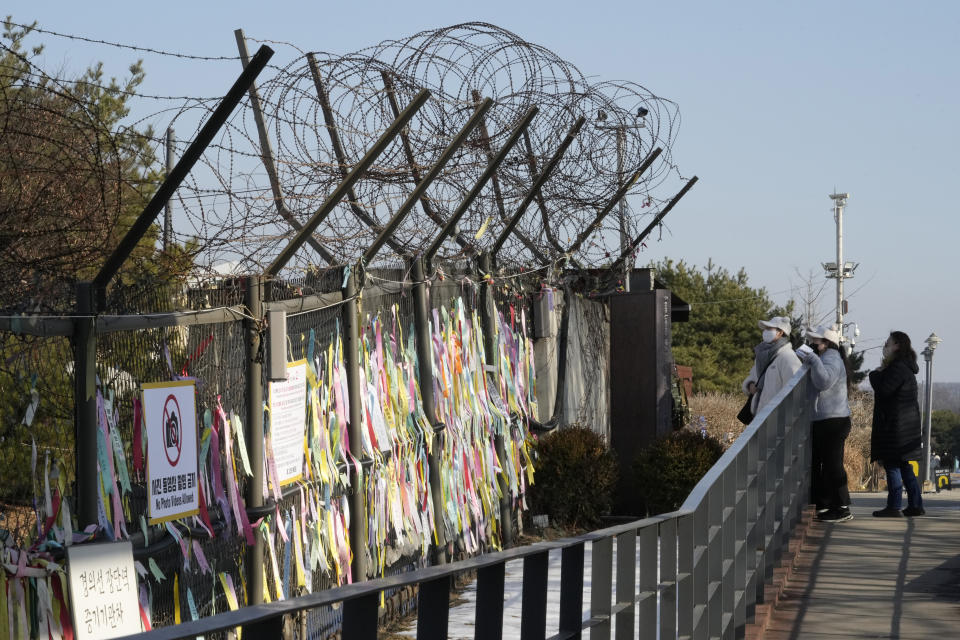 People watch ribbons placed on a barbed wire fence, wishing for the reunification of the two Koreas, at the Imjingak Pavilion near the border with North Korea, in Paju, South Korea, Wednesday, Jan. 11, 2023. North Korea's spike in missile tests, growing nuclear ambitions and other provocative acts pose a "serious threat" that could lead to a dangerous miscalculation and spark a wider conflict, South Korean President Yoon Suk Yeol said Tuesday. (AP Photo/Ahn Young-joon)