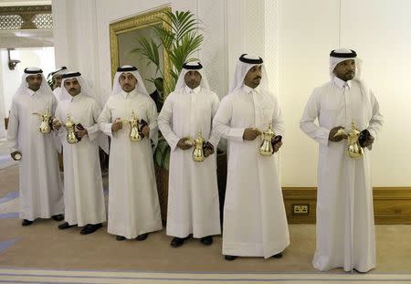 Members of staff from the Diwan Palace stand holding pots of tea as Qatar's Emir Sheikh Tamim bin Hamad al-Thani meets with US Secretary of State John Kerry in Doha, August 3, 2015. REUTERS/Brendan Smialowski/Pool