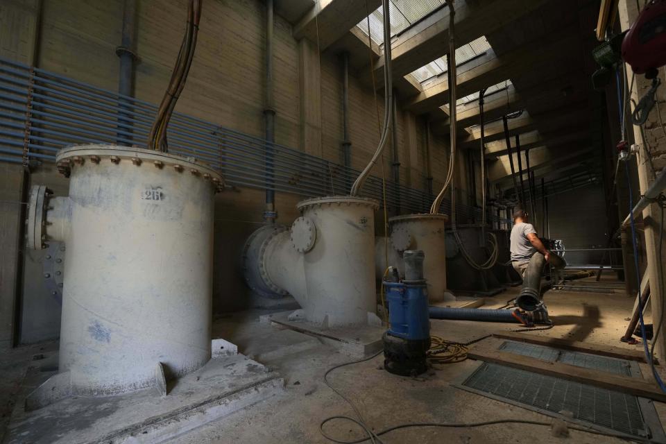 A worker moves a tube inside a dewatering pump in Boretto, Italy, on the Po river, Wednesday, June 15, 2022. The drying up of the river is jeopardizing drinking water in Italy's densely populated and highly industrialized districts and threatening irrigation in the most intensively farmed part of the country. (AP Photo/Luca Bruno)