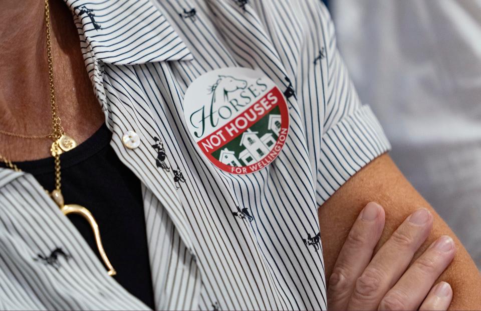 A woman wears a sticker on her shirt while attending the Wellington's Equestrian Preserve Committee meeting on whether to approve the Wellington North proposal to build new luxury homes and expand the equestrian showgrounds on June 7, 2023 in Wellington, Florida. The committee denied the proposal. 