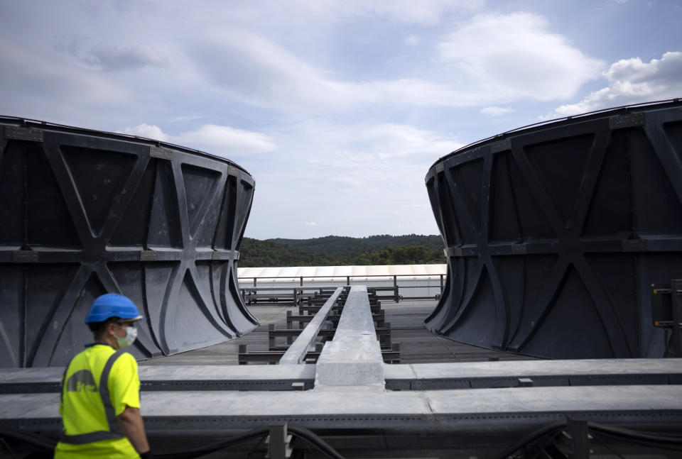 A worker surveys the cooling tower area of the ITER machine in Saint-Paul-Lez-Durance, France, Thursday, Sept. 9, 2021. Scientists at the International Thermonuclear Experimental Reactor in southern France took delivery of the first part of a massive magnet so strong its American manufacturer claims it can lift an aircraft carrier. (AP Photo/Daniel Cole)