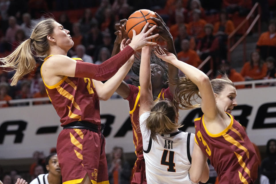 Iowa State guard Ashley Joens, left, forward Nyamer Diew, rear, and guard Denae Fritz (3) reach for a rebound with Oklahoma State guard Anna Gret Asi (4) I the second half of an NCAA college basketball game, Wednesday, Feb. 22, 2023, in Stillwater, Okla. (AP Photo/Sue Ogrocki)