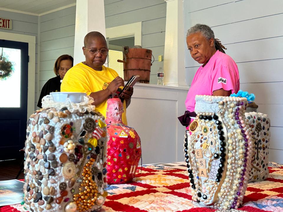 Choyce Simms Elam and Doris Williams explain the decorations on their memory jugs.