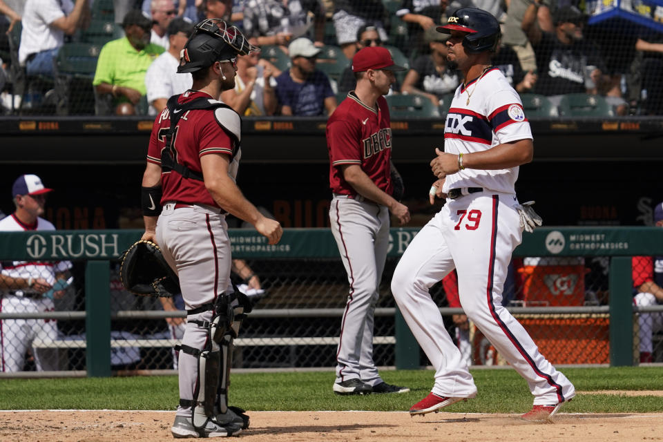 Chicago White Sox's Jose Abreu, right, scores on a sacrifice fly by Gavin Sheets as Arizona Diamondbacks catcher Cooper Hummel looks to the field during the sixth inning of a baseball game in Chicago, Sunday, Aug. 28, 2022. (AP Photo/Nam Y. Huh)