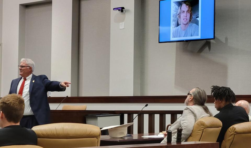 Prosecutor Mark Graham, left, points to Andre Bivins, right, who is seated by attorney John Edward Eagen, center. Graham is telling jurors that the evidence in the shooting death of Edward Ross, on the TV screen, points to Bivins as one of three men responsible for Ross' death.