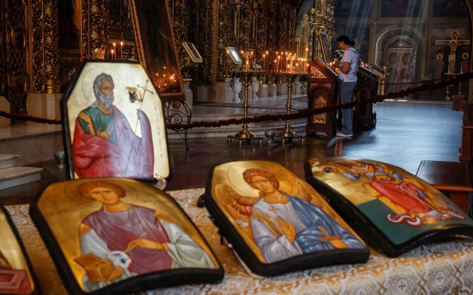 A woman lights a candle before a ceremony of blessing of Orthodox icons drawn on armoured plates - GLEB GARANICH/REUTERS