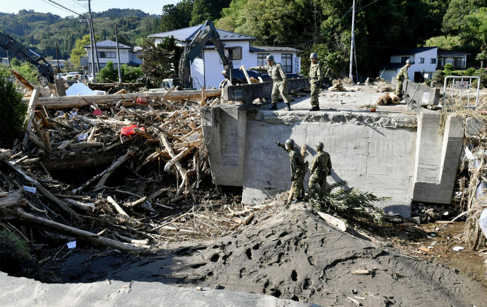 Japan's Self-Defense Forces' members work to remove piled driftwood at a bridge after Typhoon Hagibis hits the town in Marumori, Miyagi prefecture, northern Japan Wednesday, Oct. 16, 2019. The typhoon hit Japan's main island on Saturday with strong winds and historic rainfall that caused more than 200 rivers to overflow, leaving thousands of homes flooded, damaged or without power. (Kyodo News via AP)