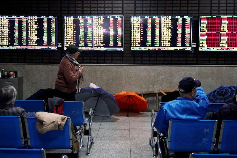 Investors look at screens showing stock information at a brokerage house in Shanghai