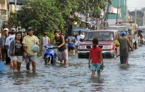 Philippine commuters maneuver through floodwaters in Calumpit town, 50 kilometres north of Manila. As floods which have swamped parts of the Philippines and affected more than two million people extend into their second week, the dead and the living are sharing premium space on dry ground