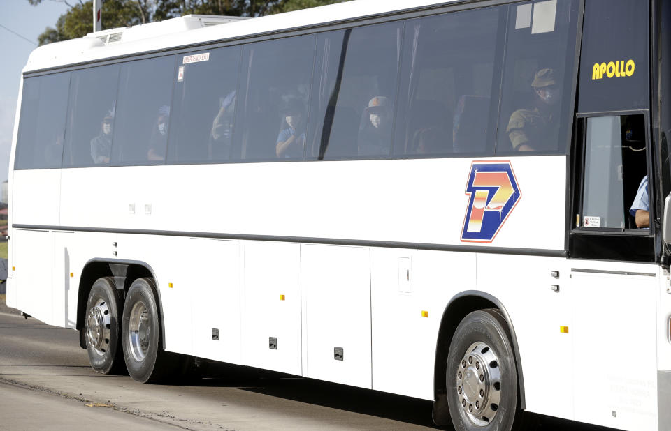 Crew from the cruise ship Ruby Princess are bussed from Port Kembla as authorities prepare for the ship's departure in Wollongong, Thursday, April 23, 2020. The Ruby Princess has been ordered to leave Australia after disembarking passengers in Sydney in March that have tested positive for COVID-19. (AP Photo/Rick Rycroft)