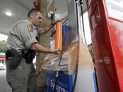 New Hanover Sheriff's deputy J. Brown wraps a gas pump for protection in Wilmington, N.C., as Hurricane Florence threatens the coast Thursday, Sept. 13, 2018. (AP Photo/Chuck Burton)