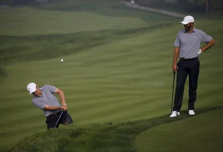 U.S. team member Jordan Spieth hits out of a bunker on the sixth hole as his team mate Dustin Johnson (R) looks on during the practice round for the 2015 Presidents Cup golf tournament at the Jack Nicklaus Golf Club in Incheon, South Korea, October 7, 2015. REUTERS/Kim Hong-Ji