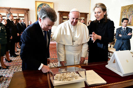 Pope Francis (C) receives the "Bun of the peace" from Colombia's President Juan Manuel Santos (L) and his wife Maria Clemencia Rodriguez (R) at the Vatican December 16, 2016. REUTERS/Vincenzo Pinto