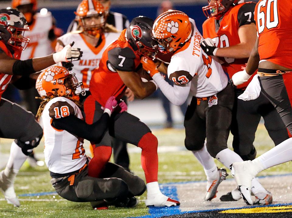 Mansfield Senior High School's Maurice Bradley II (18) and DaJohn Corbin (13) tackle Toledo Central Catholic High School's Tyler Morgan (7) during their OHSAA Division III Region 10 high school football semifinal game action Friday, Nov. 10, 2023 at Bob Bishop Stadium in Clyde. TOM E. PUSKAR/MANSFIELD NEWS JOURNAL