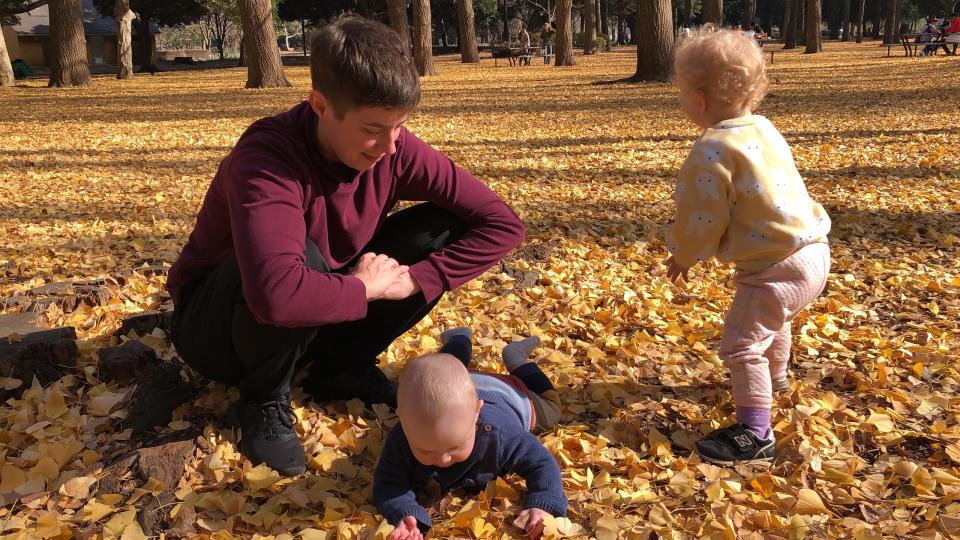 Mother with two young children playing with leaves in Japan