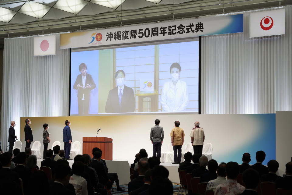 Japan's Emperor Naruhito and Empress Masako are seen on a screen during a ceremony to mark the 50th anniversary of Okinawa's return to Japan after 27 years of American rule, in Tokyo, Japan Sunday, May 15, 2022. The ceremonies are held in Tokyo and Okinawa simultaneously. (Rodrigo Reyes Marin/Pool Photo via AP)