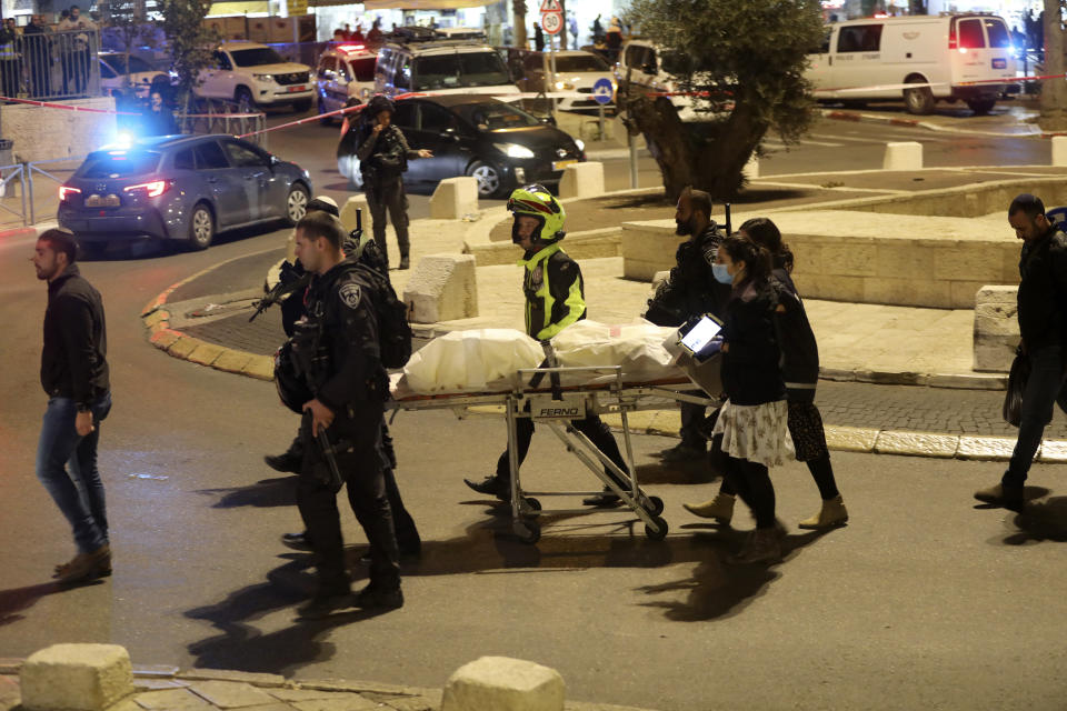 Israeli police men and paramedics carry the body of a man shot near Damascus Gate in the Old City of Jerusalem, Saturday, Dec. 4, 2021. Israeli police shot a Palestinian on Saturday after an ultra-Orthodox Jewish man was stabbed and wounded near Damascus Gate in Jerusalem's Old City, a crowded area that is often the scene of demonstrations and clashes. (AP Photo/Mahmoud Illean)