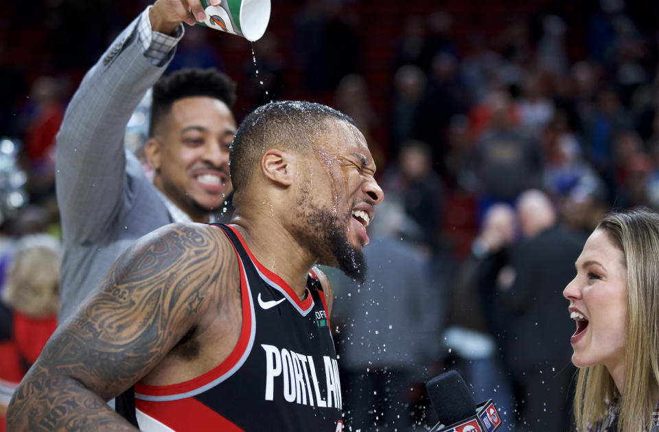 Portland Trail Blazers guard Damian Lillard, center, gets doused by guard CJ McCollum after Lillard scored 61 points against the Golden State Warriors in an NBA basketball game in Portland, Ore., Monday, Jan. 20, 2020. The Trail Blazers won 129-124 in overtime. (AP Photo/Craig Mitchelldyer)