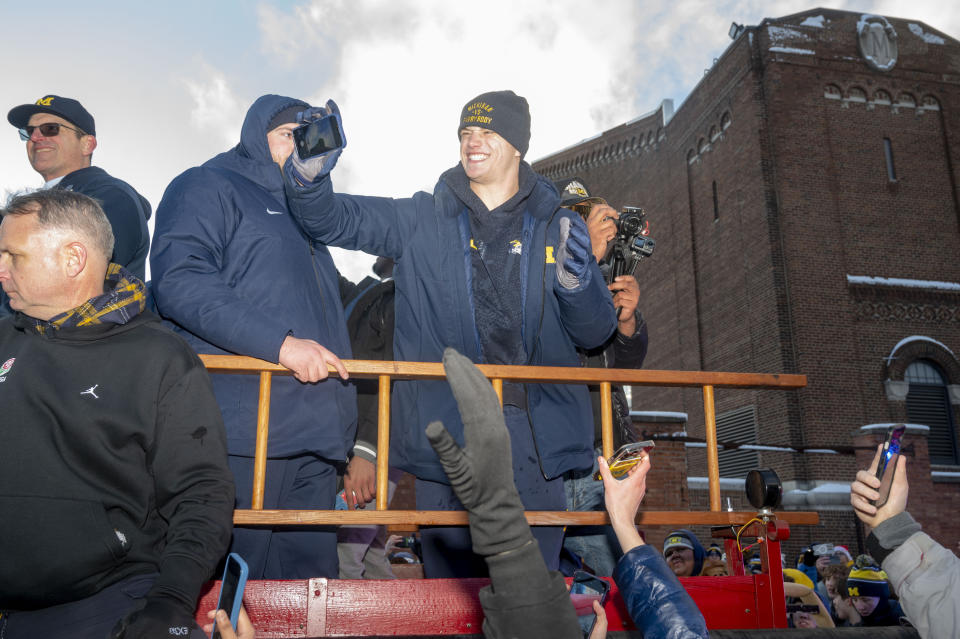 Michigan quarterback J.J. McCarthy (9) grabs a fan's phone for a selfie during a parade celebrating Michigan's college football title, in Ann Arbor, Mich., Saturday, Jan. 13, 2024. (Jacob Hamilton/Ann Arbor News via AP)