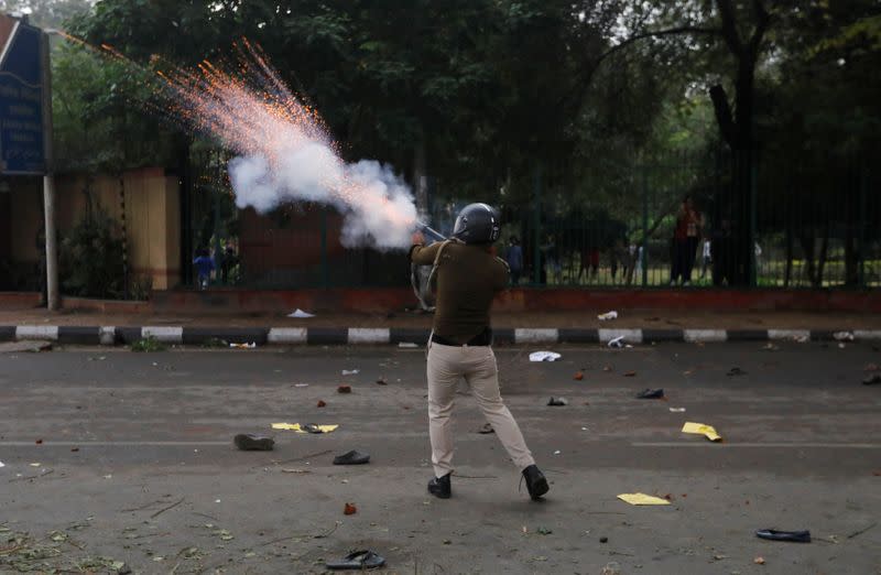 A police officer fires a teargas shell during a protest against the Citizenship Amendment Bill in New Delhi