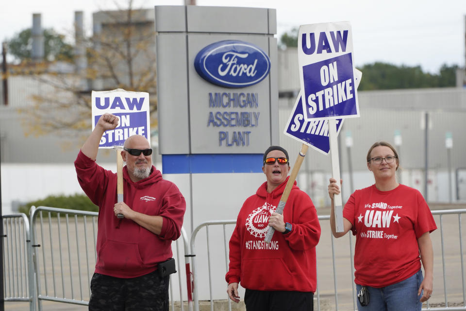 File - United Auto Workers members walk the picket line at the Ford Michigan Assembly Plant in Wayne, Mich., Sept. 26, 2023. Ford Motor Co. swung to a net loss in the fourth quarter due to a large accounting charge on pension plans and the effects of a six-week strike at multiple factories by the United Auto Workers union. (AP Photo/Paul Sancya, Ford)