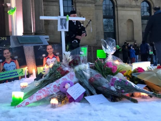 People left candles, cards and flowers to remember Lexi Daken outside of the provincial Legislative Assembly building in Fredericton on Sunday. (Gary Moore/CBC - image credit)