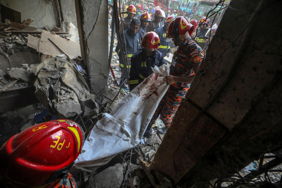 Fire officials carry a body of a victim after an explosion in a commercial building, in Dhaka, Bangladesh, Tuesday, March 7, 2023. An explosion in a seven-story commercial building in Bangladesh's capital has killed at least 14 people and injured dozens. Officials say the explosion occurred in a busy commercial area of Dhaka. (AP Photo/Abdul Goni)