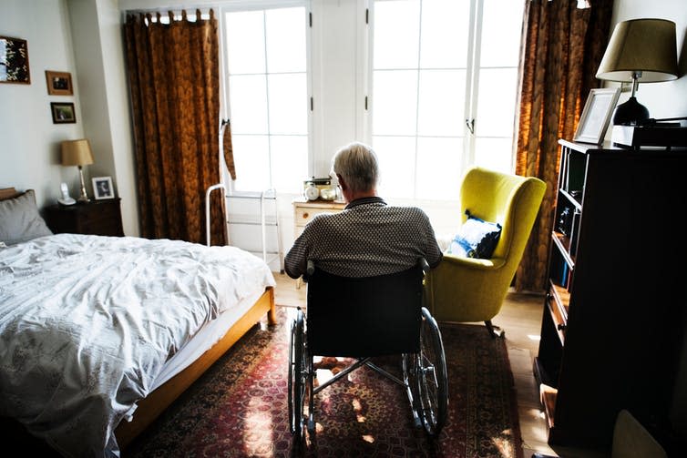 Older man in wheelchair in bedroom.