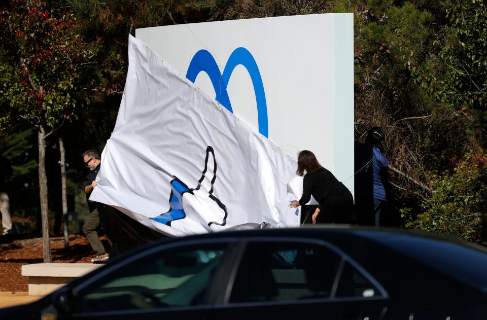 Facebook employees unveil a new logo and the name company name Meta on the sign in front of Facebook headquarters on Oct. 28 in Menlo Park, Calif., after CEO Mark Zuckerberg announced the changes.