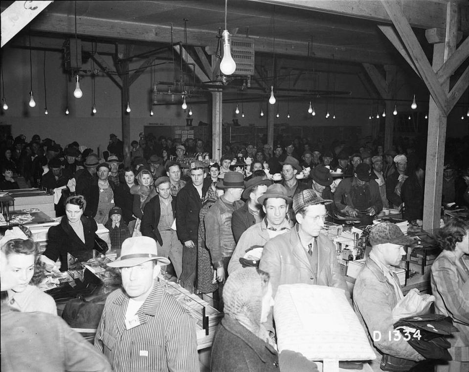 Workers line up to buy items at a Hanford camp store. With 51,000 people living in the camp during the war, the handful of hastily constructed stores at the site were kept busy. Residents also could catch a bus into Pasco for shopping.