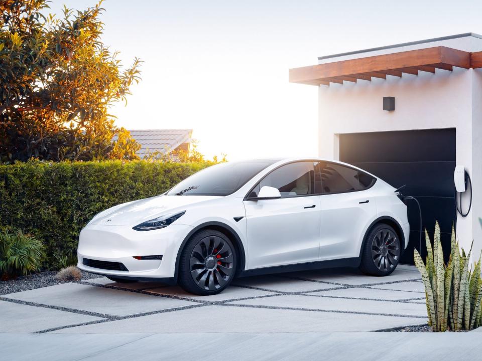 The Tesla Model Y electric SUV charging at a home.