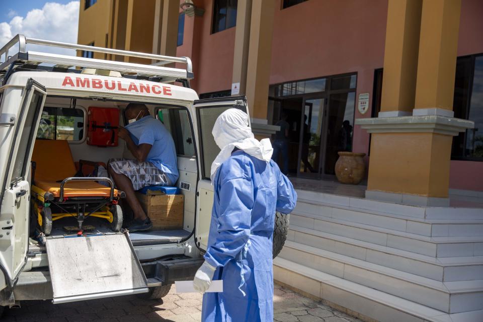 Workers of the national ambulance center load a man who was deported from the United States two weeks ago and who is tested positive with the new coronavirus, to take him from the hotel he was being quarantined, to the hospital in Tabarre, Haiti, Sunday, April 19, 2020. (AP Photo/Dieu Nalio Chery)