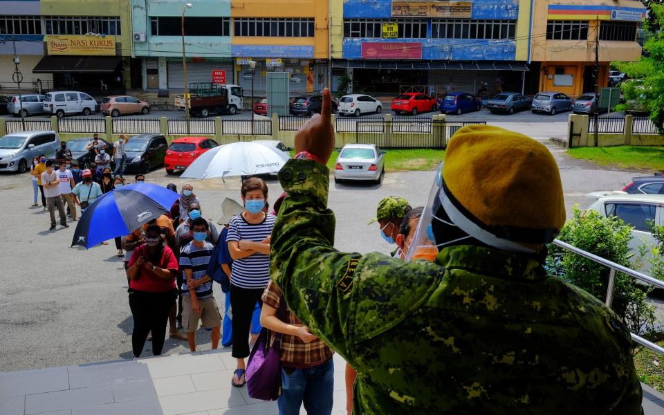 People stand in line outside at a temporary Covid-19 testing center set up at the Subang Jaya City Council (MBSJ) public hall in Petaling Jaya, Malaysia -  Samsul Said / Bloomberg