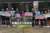 Joephy Chan, Hong Kong legislative councillor, center in pink, and members of the pro-Beijing labor group, the Hong Kong Federation of Trade Unions, hold posters as they stage a protests against the release of treated radioactive water from Fukushima near the Japanese embassy in Hong Kong, Tuesday, Aug 22, 2023. Hong Kong will ban Japanese seafood products imported from 10 prefectures after Japan announced to release Fukushima waste water from Thursday. (AP Photo/Katie Tam)