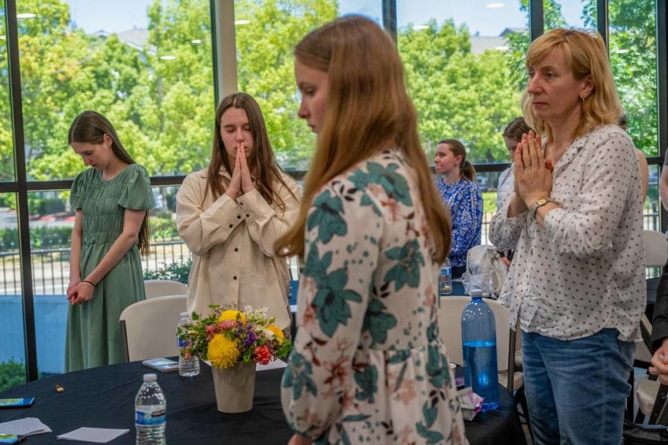 Ukrainian refugee high school graduates say a prayer Tuesday with their family at an event after they completed their National Multi-subject Test, or NMT, at the Ukrainian American House in Rancho Cordova.