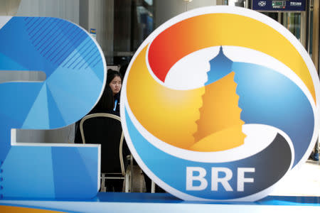 A member of the security personnel sits behind a logo of the Belt and Road Forum (BRF) at the China National Convention Center, in Beijing, China, April 25, 2019. REUTERS/Jason Lee