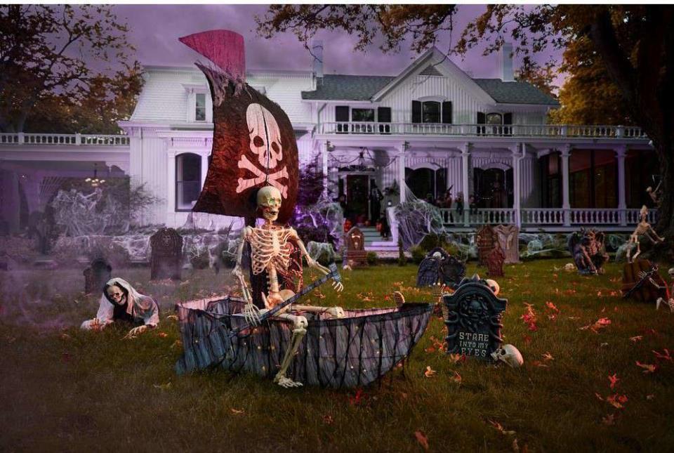 A faux pirate ship halloween decoration in the front yard of a white house after dark