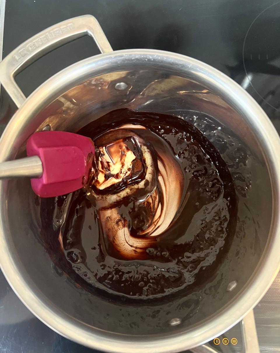 Butter being stirred into a brown chocolate mixture in a saucepan.